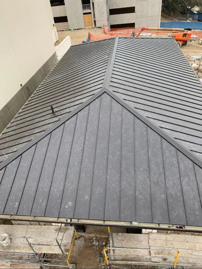Commercial metal roof construction with crane equipment in Applewood
